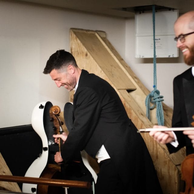 A cellist and violinist get their instruments ready backstage