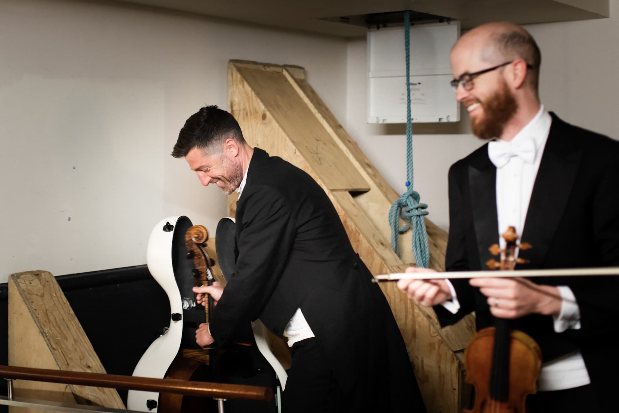 A cellist and violinist get their instruments ready backstage
