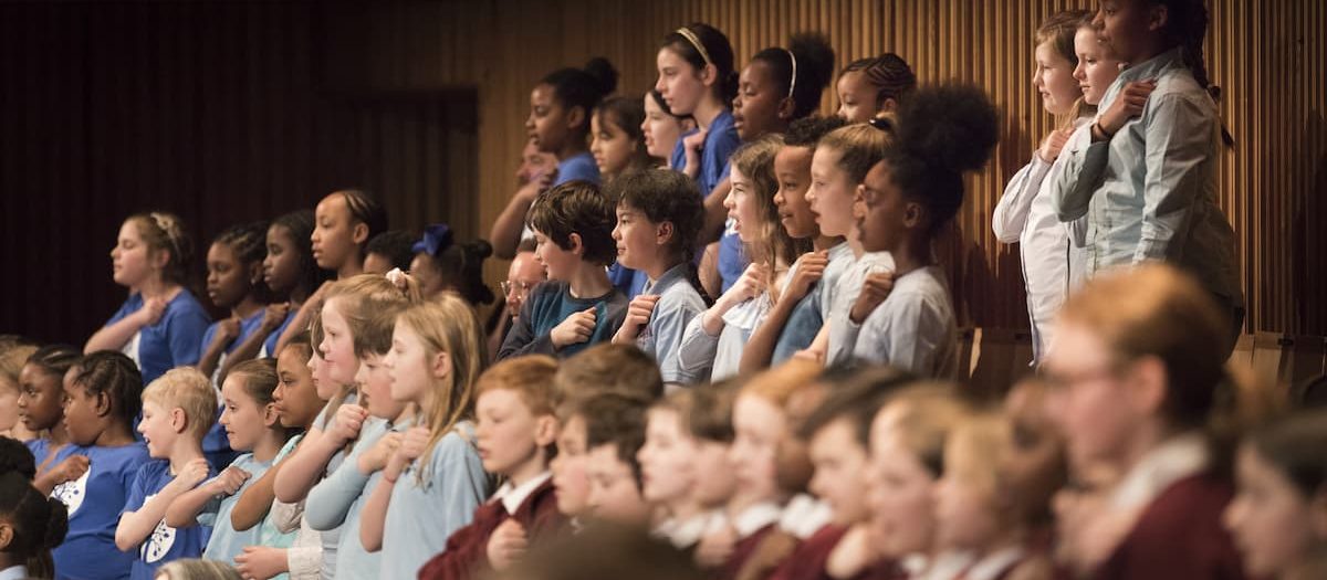 Children standing and singing along at a concert