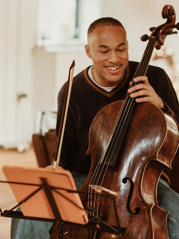 Cellist Sheku Kanneh-Mason seated with cello and bow.