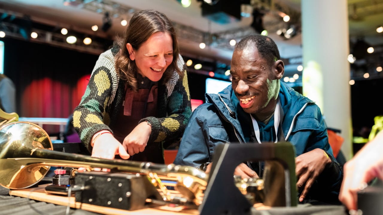Woman and man smiling next to accessible trombone