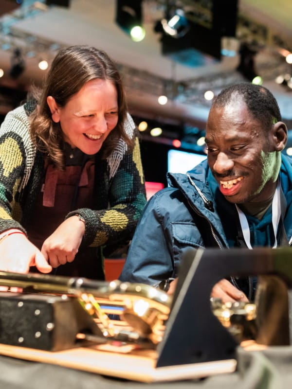 Woman and man smiling next to accessible trombone