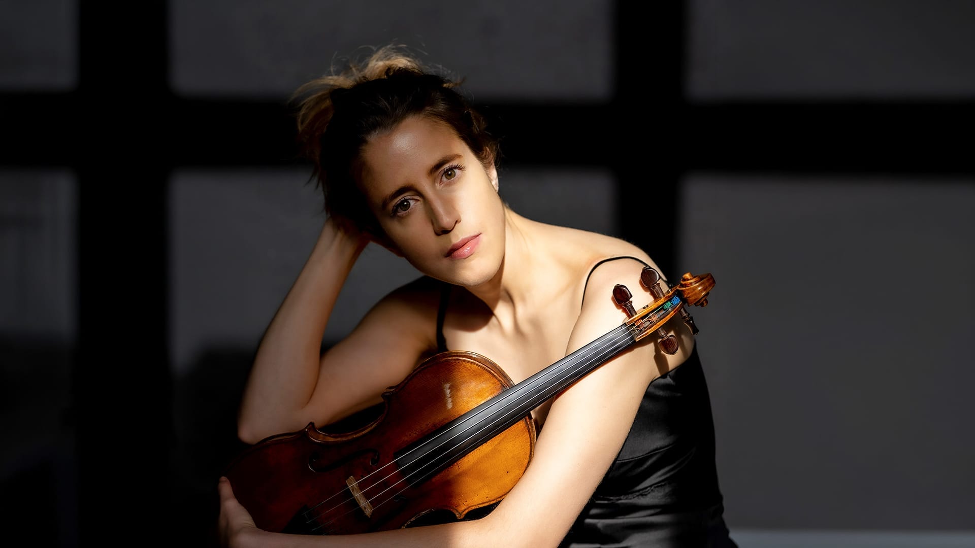 Violinist Vilde Frang, a woman with blonde hair, wearing a black dress, holding a violin.
