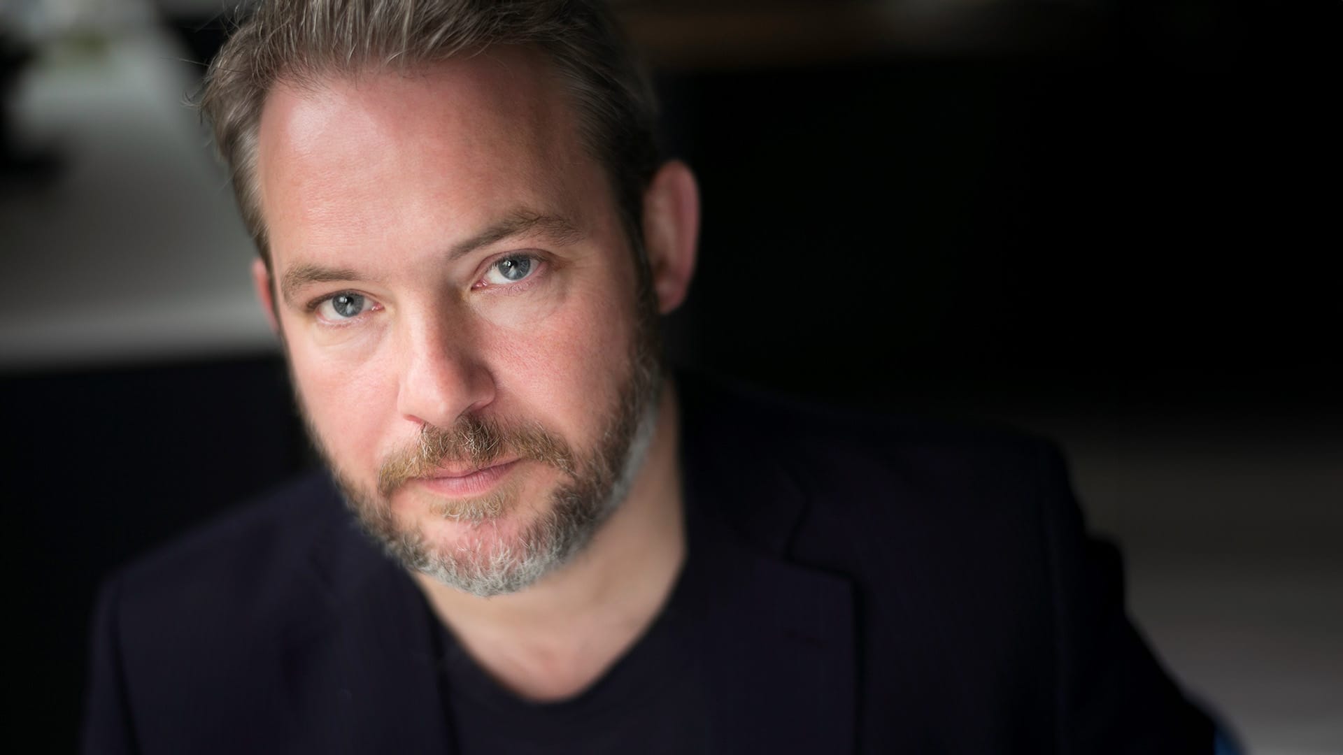 Tenor Robert Murray, a man with a light beard and black t-shirt, portrait