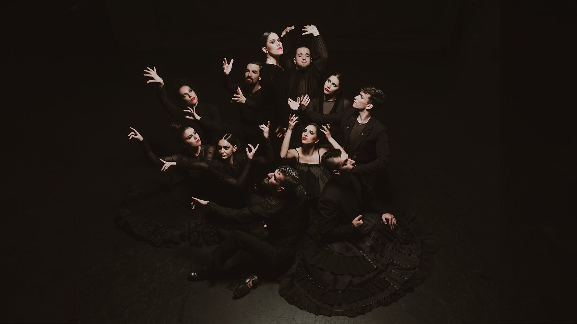 Dancers from Ballet Flamenco de Andalucía pose against a black background.