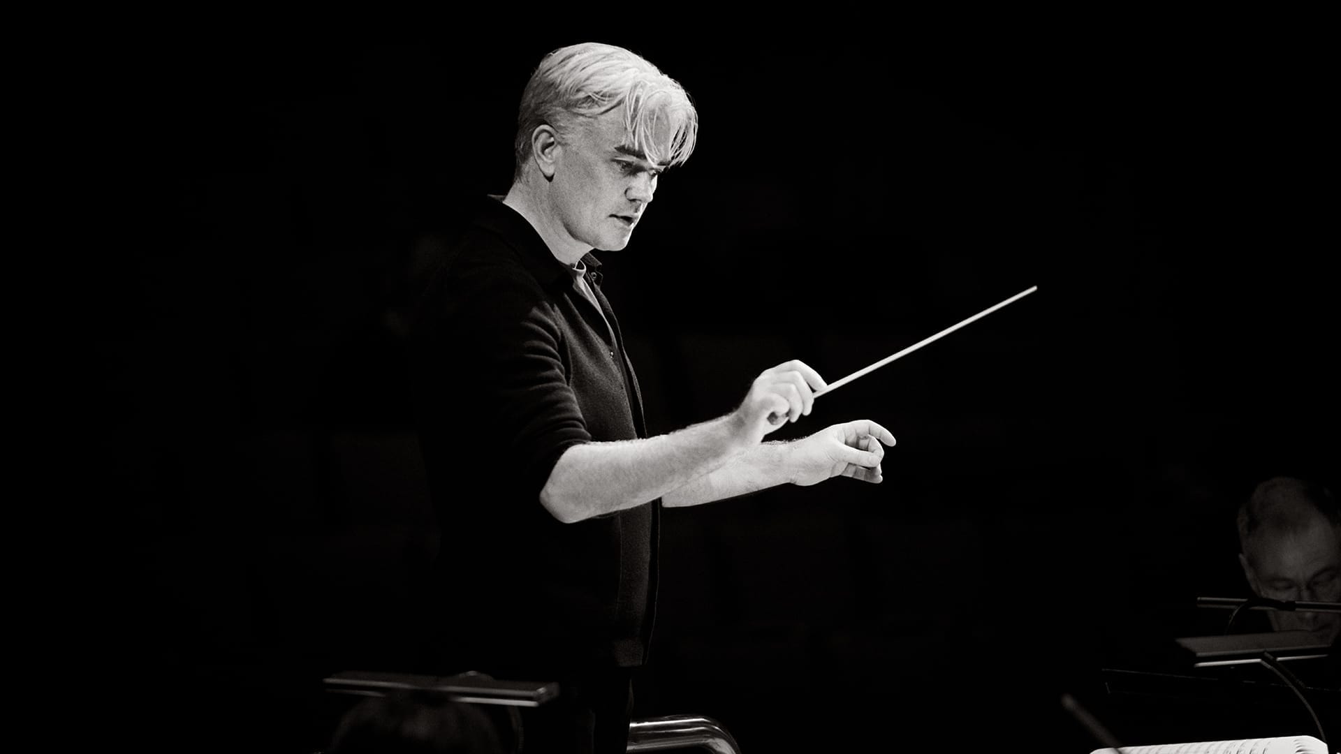 Conductor Edward Gardner, a man with short silver hair, conducting with a baton, black and white photograph.