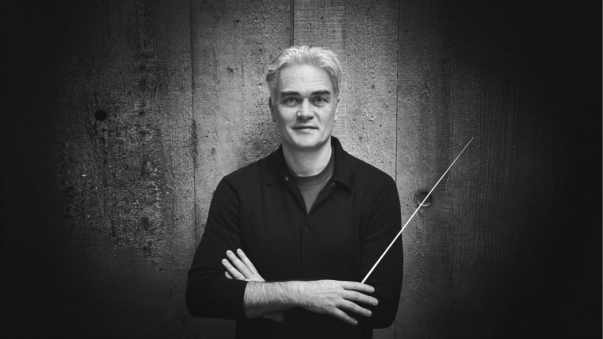 Conductor Edward Gardner, a man with short silver hair, holding a conductor's baton and smiling at the camera