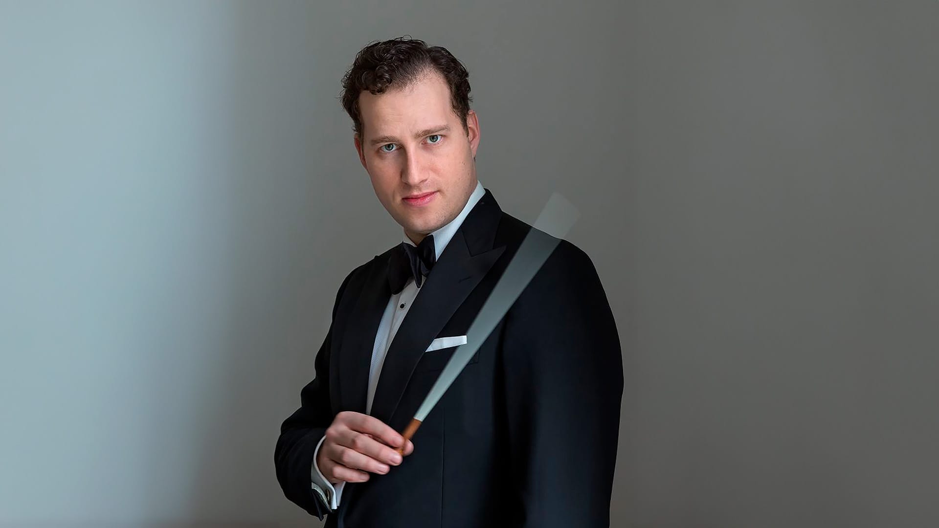 Conductor Nikolaj Szeps-Znaider, formal portrait, holding a conductor's baton and looking directly into the camera.